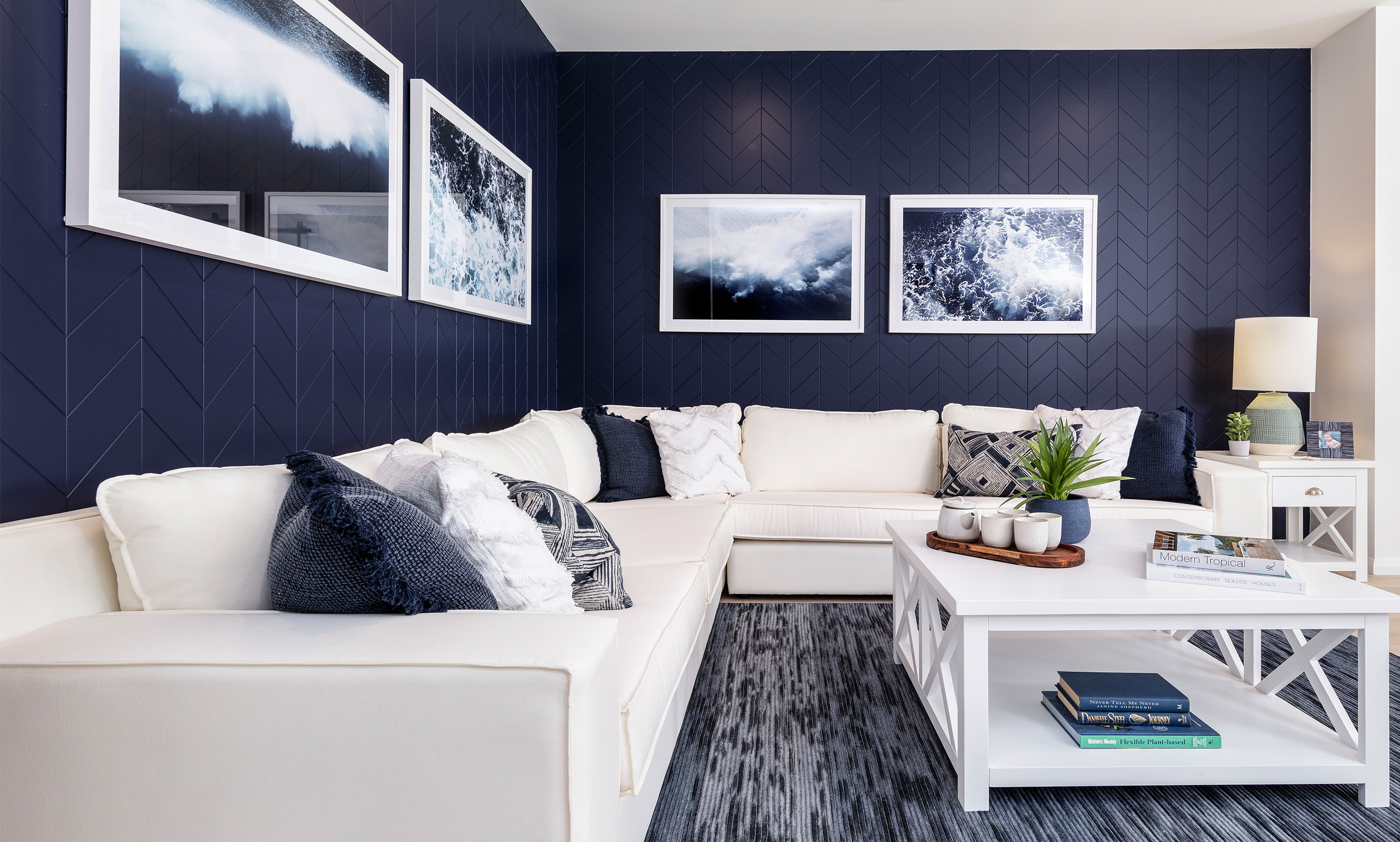 Royal blue feature wall in the chevron patterned wall panelling and crisp classic white furiture with coastal paintings continuing the royal blue hue.