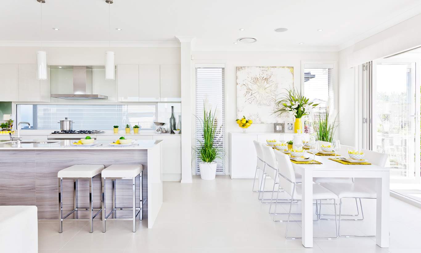 A kitchen & dining area decorated with bright potted plants, flowers & citrus