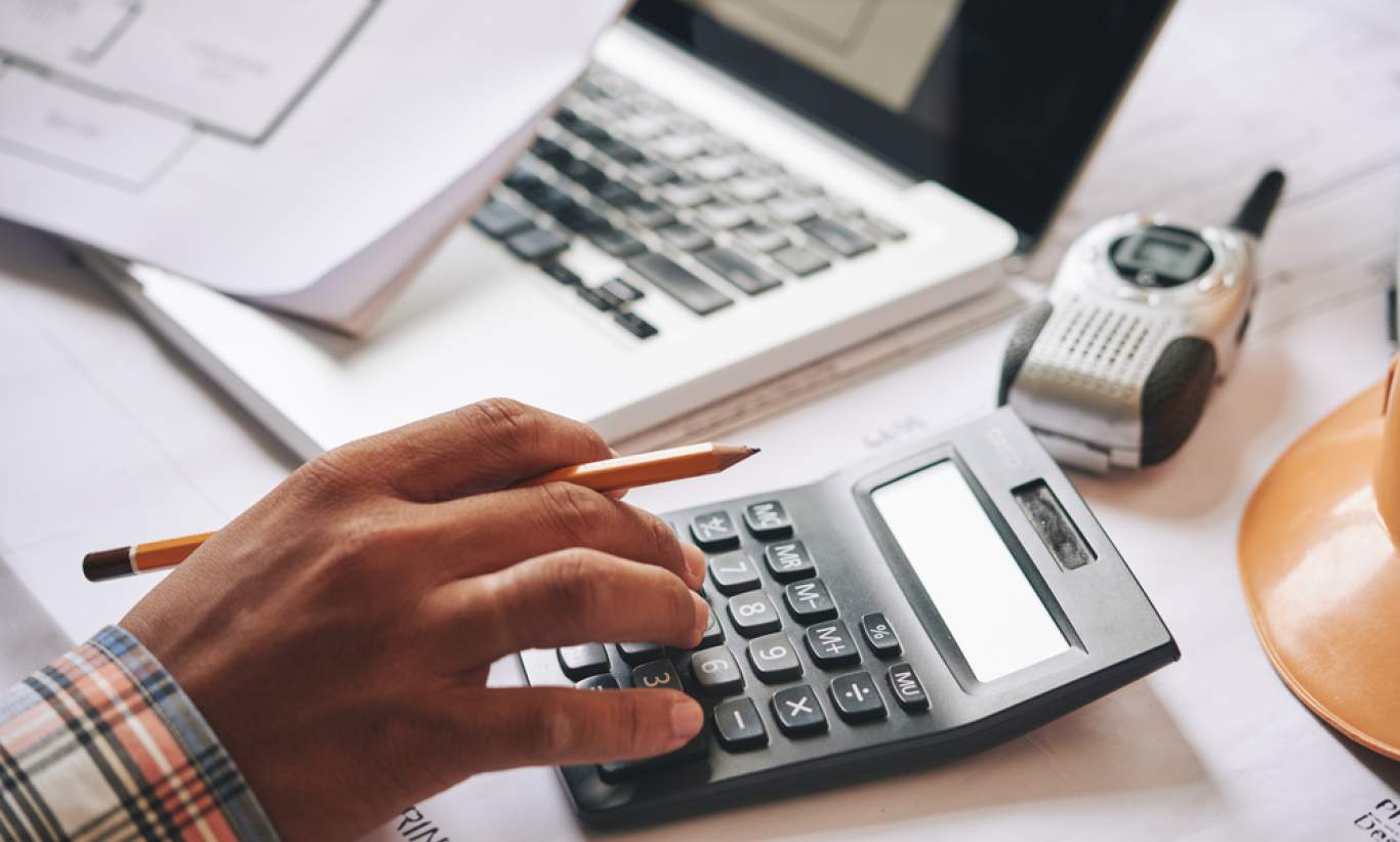 Businessman calculating budget before signing real estate project contract with house and car model at the table in the office