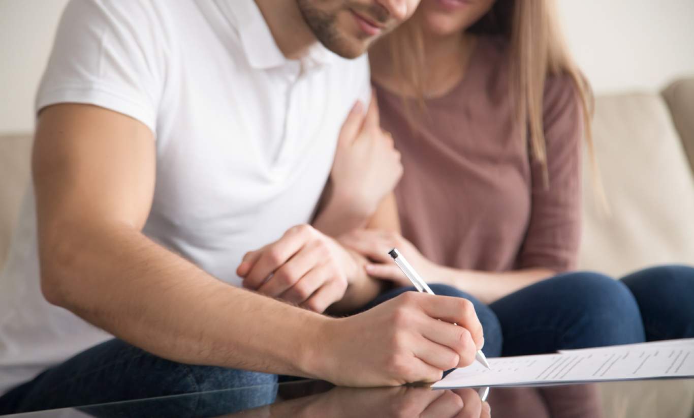 A couple signing documents for their first home.