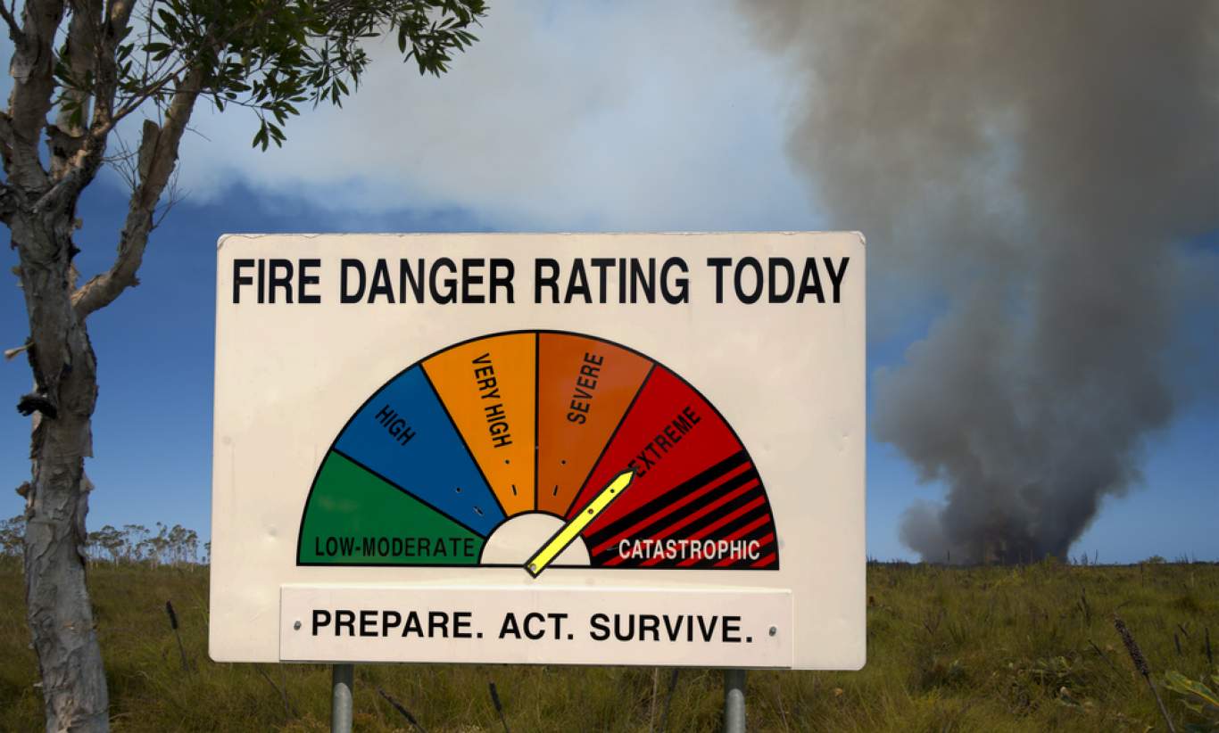 A fire danger warning set to extreme with smoke in the distance