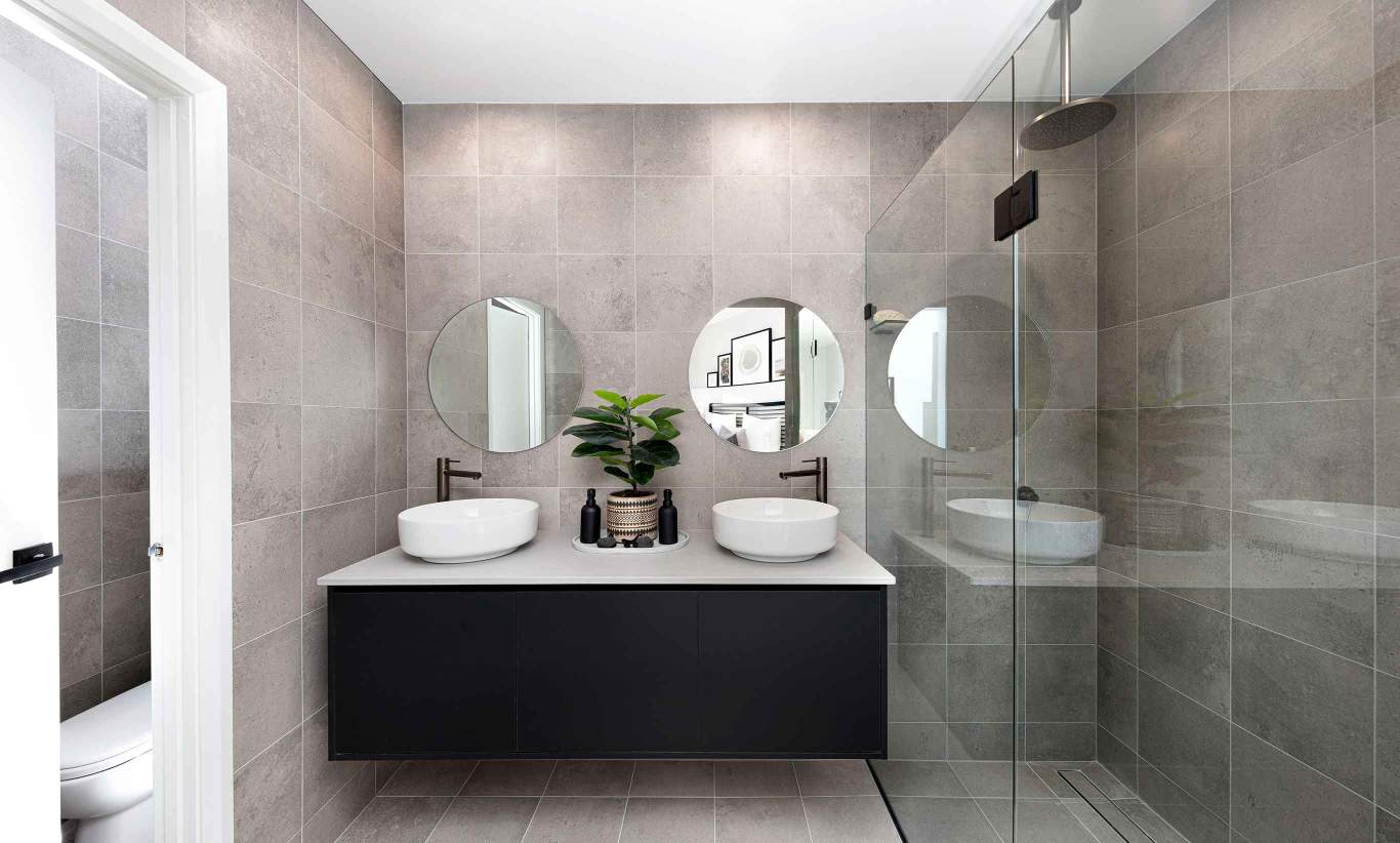 Dark and modern bathroom with gray wall tiles, stone like washbasin and big mirror