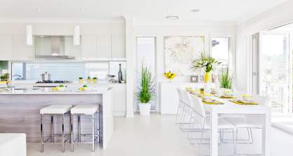 A kitchen & dining area decorated with bright potted plants, flowers & citrus