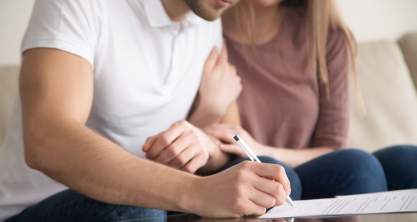 A couple signing documents for their first home.